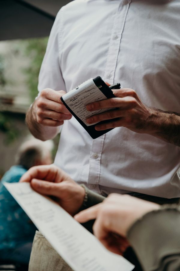 O servitoare într-un restaurant stând lângă un client care verifică nota de plată | Sursa: Unsplash